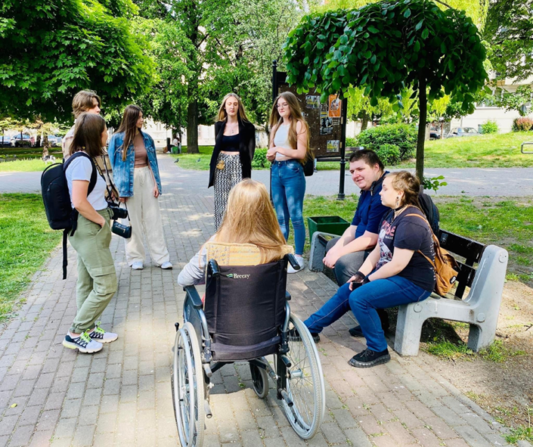 Grupa znajomych w parku, w tym osoba poruszająca się na wózku.